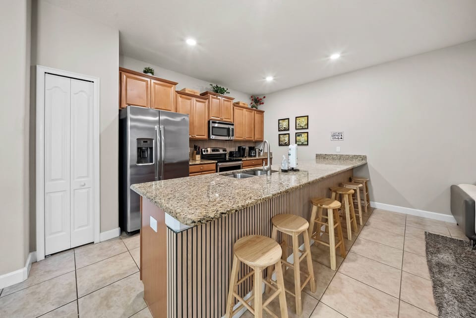 Enjoy a stylish kitchen with warm wooden cabinetry and sleek granite countertops that balance comfort and functionality. The spacious island is perfect for casual dining, and modern appliances cater to all your culinary needs.
