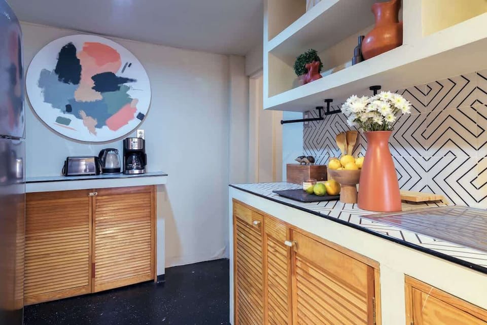 Modern kitchen area with ample counter space, open shelving, and essential appliances for an easy and seamless stay. Perfect for travelers who value comfort, convenience, and feeling at home while away.