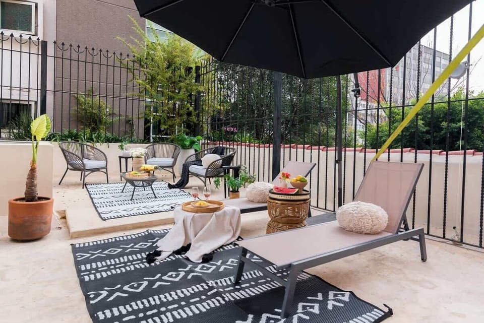 A stylish rooftop lounge with sunbeds and shaded seating, perfect for relaxing under the sun or enjoying a laid-back afternoon outdoors.
