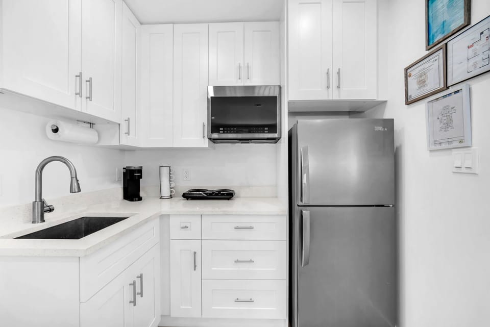 Compact kitchenette with a refrigerator, two-burner electric stove, microwave, Keurig, and ample cabinet storage for short or long stays.