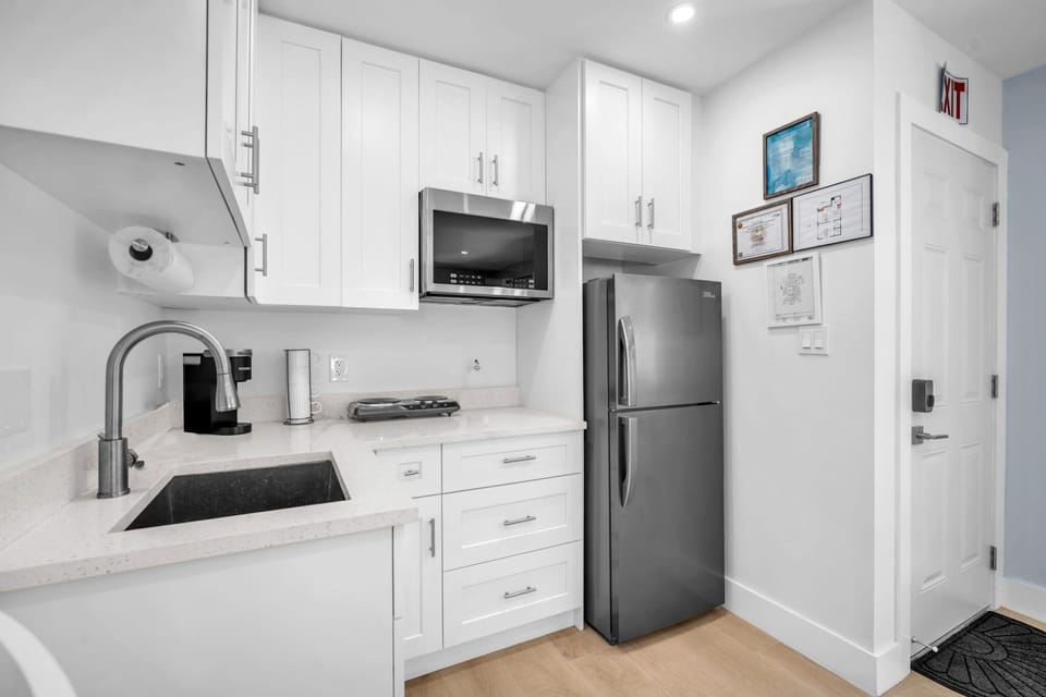 Compact kitchenette with a refrigerator, two-burner electric stove, microwave, Keurig, and ample cabinet storage for short or long stays.