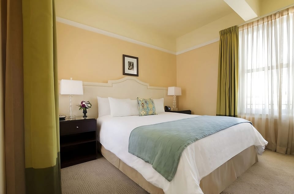 Stretch out on a plush bed beside softly filtered daylight.