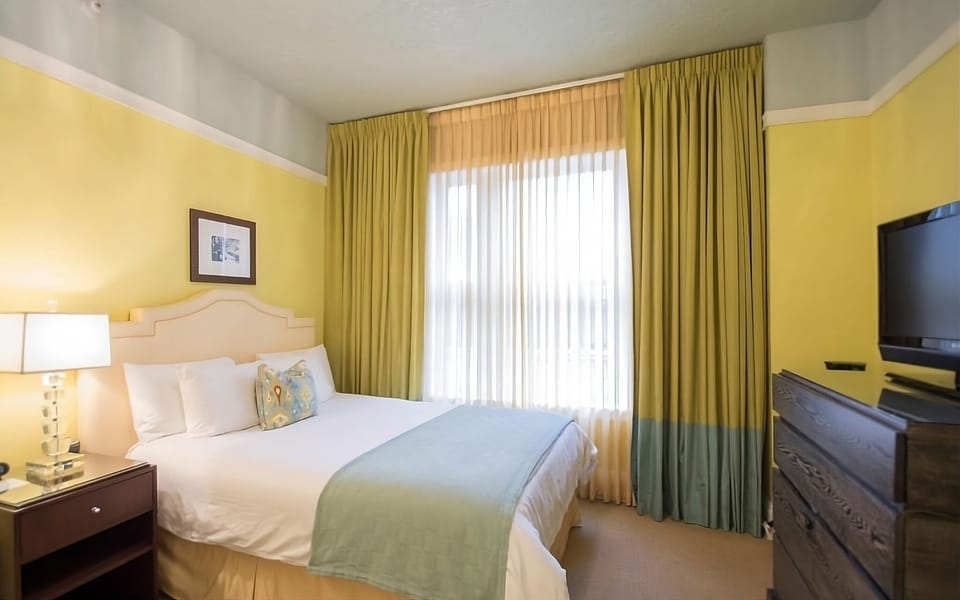 Unwind in crisp linens beside sunny windows and soft drapes.