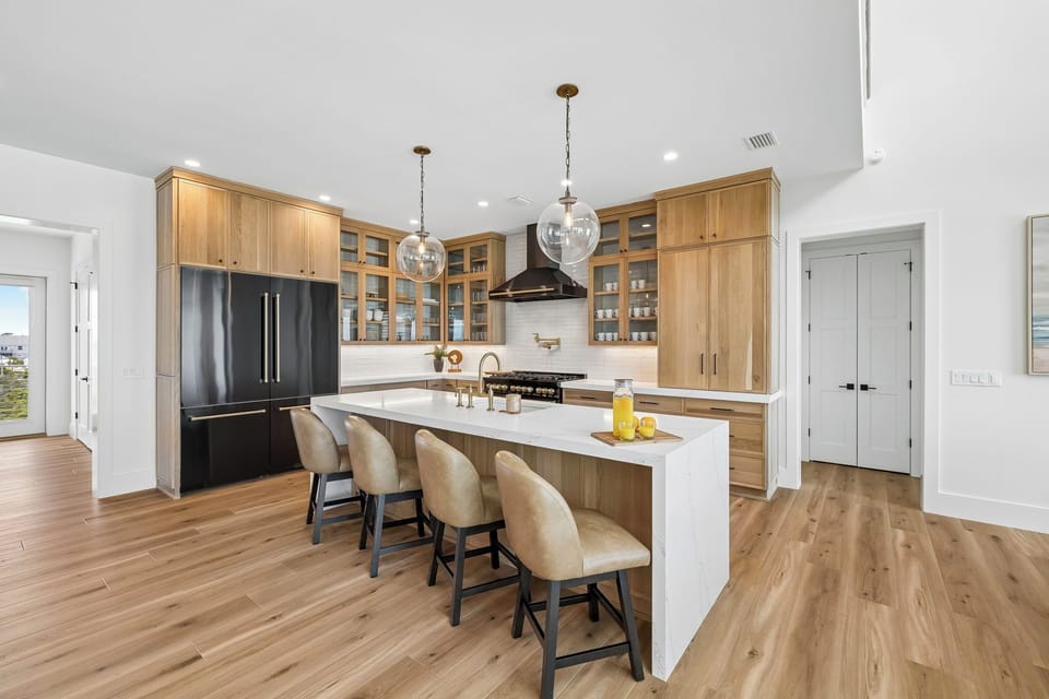 Gather around the spacious kitchen island with warm wood tones, marble counters, and gleaming fixtures—your home base for morning coffee and meal prep during your stay.