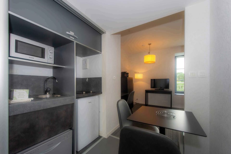 Two-ring ceramic hob, dishwasher, Nespresso machine, and a small dining table — a fully equipped kitchen in a compact space.