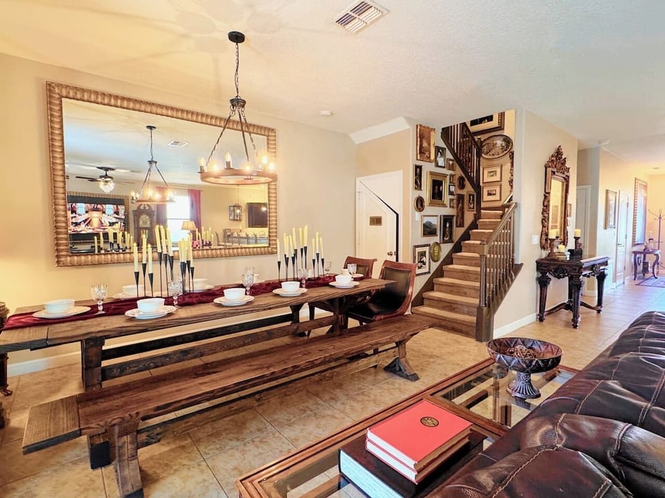 Candelabras glowing, burgundy place settings, golden skeleton keys scattered on rustic wood, gallery staircase rising behind a gilded mirror. Set the table and let dinner become the main event.