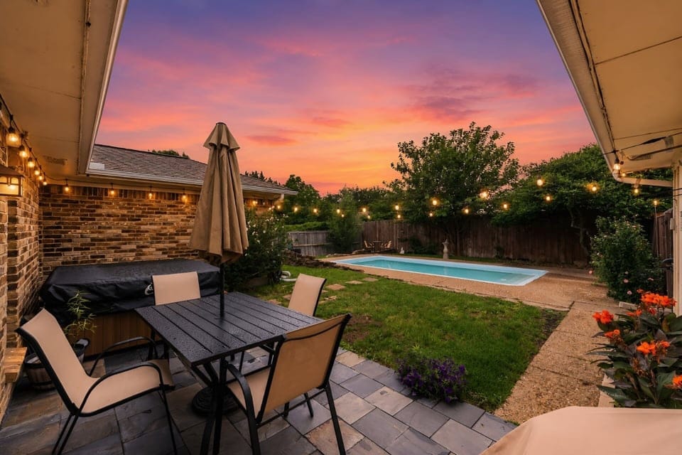 Private backyard with a pool and ambient lighting—perfect for unwinding under the Texas sunset after an exciting day.