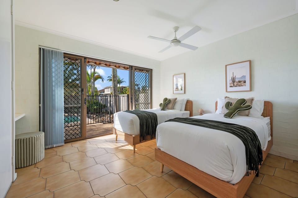 Twin bedroom with ceiling fan and poolside access.