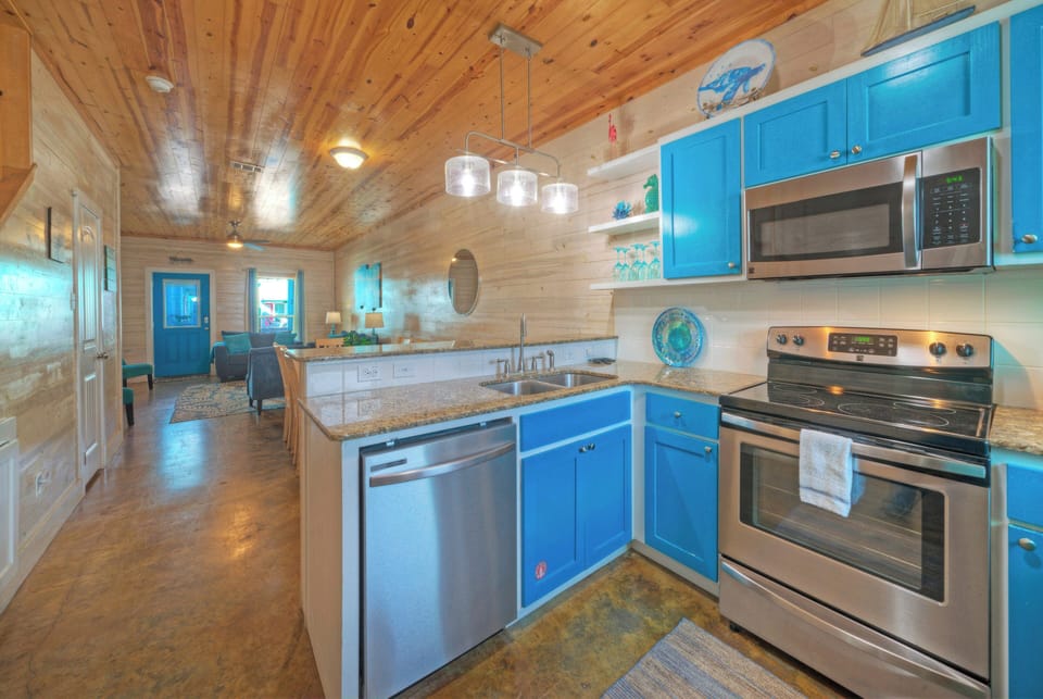 Bright, beachy kitchen with coastal-blue accents, stainless appliances, and easy flow into the dining and living spaces.