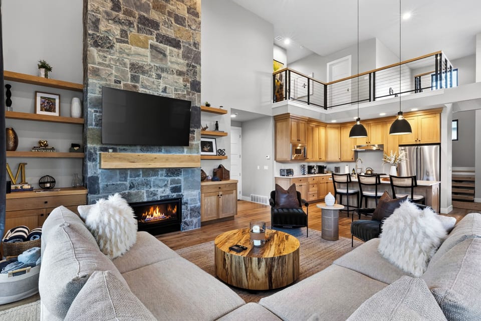 Modern great room with soaring ceilings, a stone fireplace, and cozy mountain-luxe style.