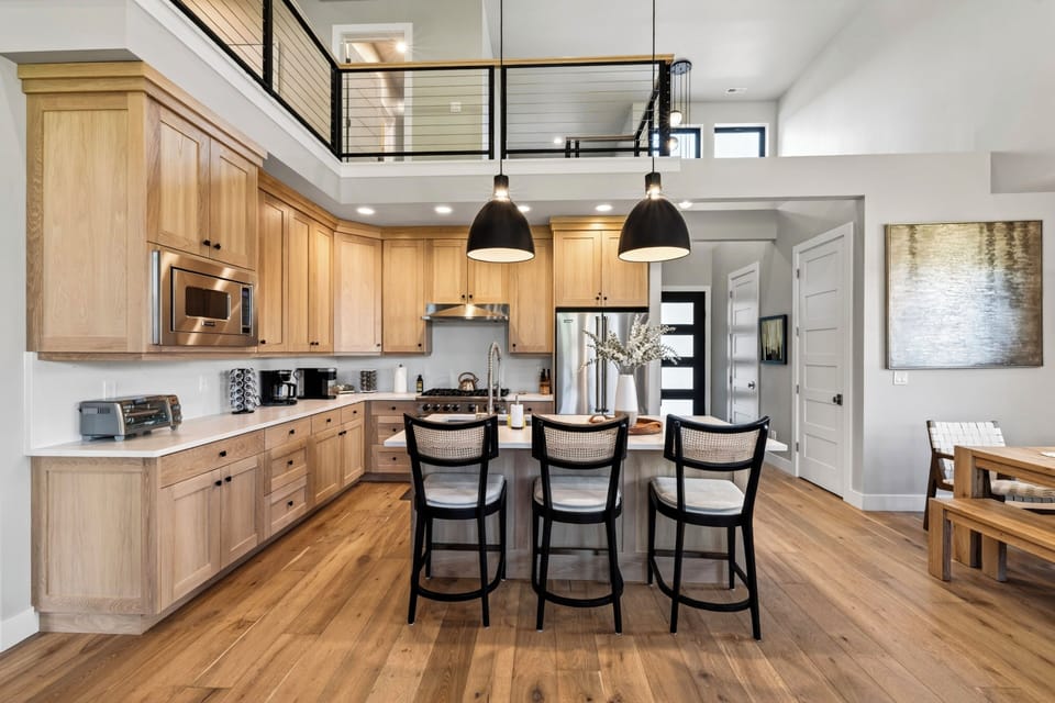 Chef’s kitchen with warm wood cabinetry, island seating, and an airy lofted layout.
