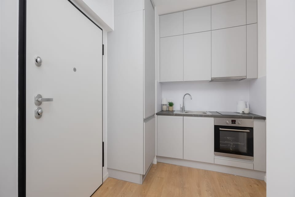 A sleek kitchen with white cabinets, dark countertops, and integrated appliances arranged along one wall. Contemporary finishes create a polished appearance.