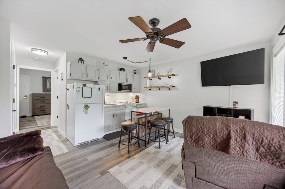 Step into your cozy, open-plan retreat where a fully equipped kitchen, comfortable seating, and modern entertainment await. The ceiling fan keeps you cool while you relax in this bright, welcoming space.