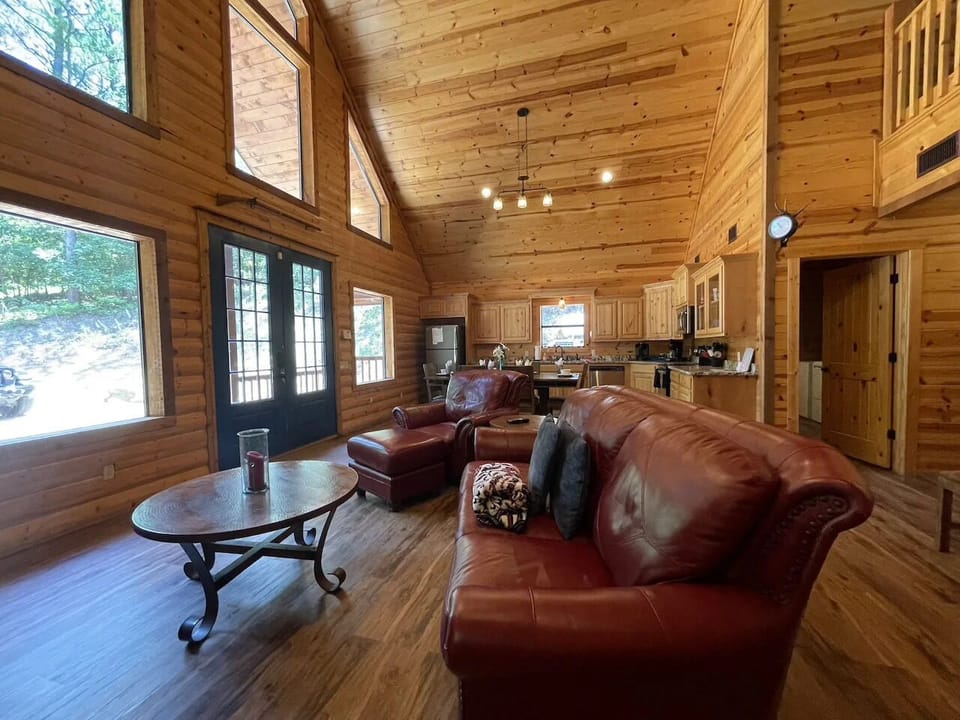 Sink into rich leather sofas in your open-concept cabin, where vaulted pine ceilings and walls create a warm, natural retreat. The full kitchen and abundant natural light invite you to cook, gather, and unwind in rustic comfort.