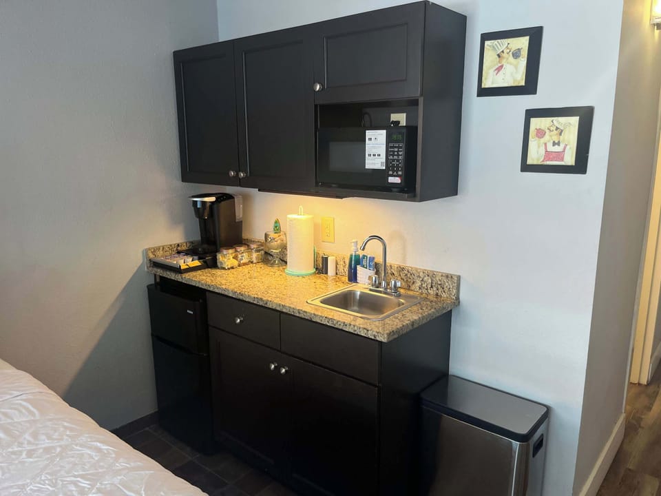 Compact kitchenette station equipped with a microwave, coffee maker, sink, and mini fridge