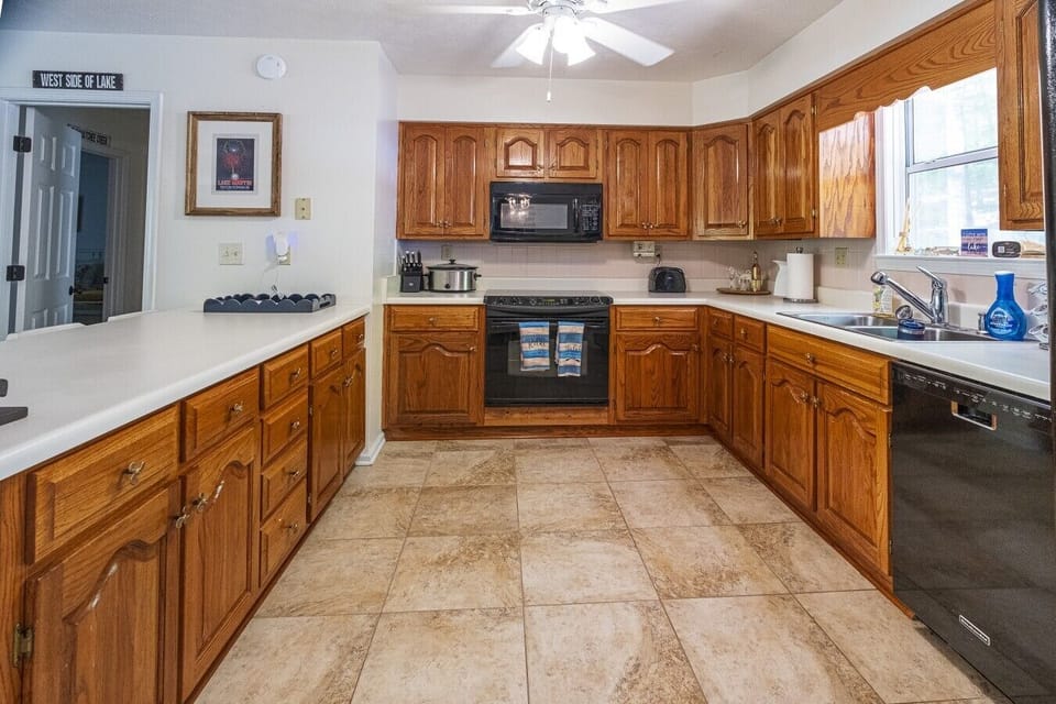 Kitchen | Wood Cabinetry & Black Appliances | Wraparound Counters & Tile Flooring