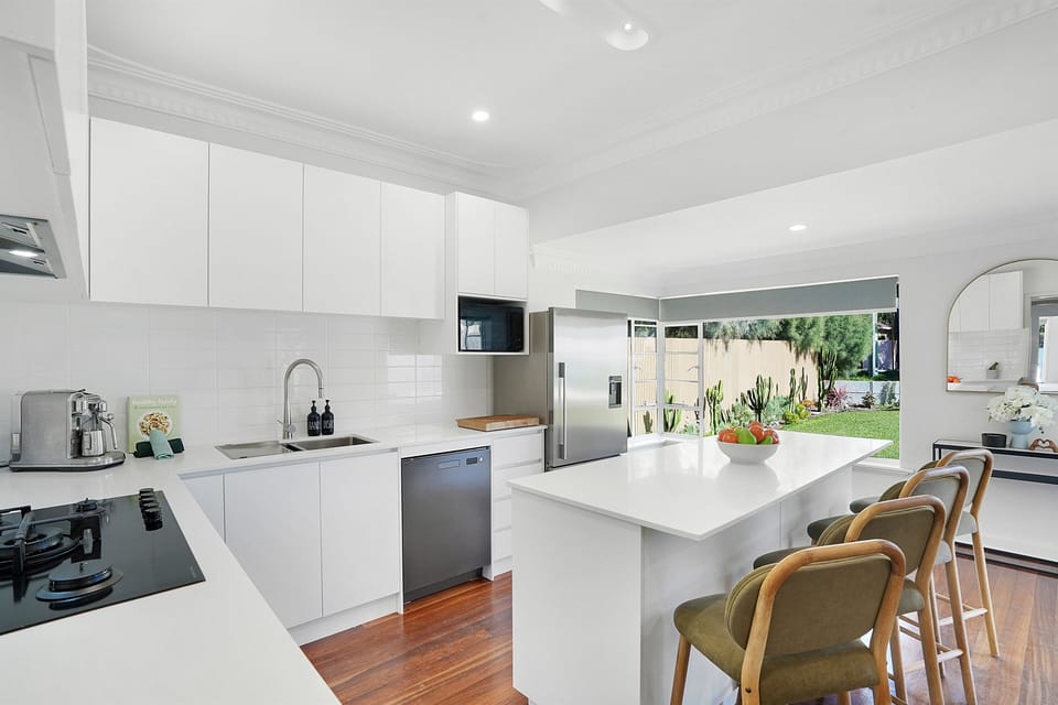 Bright and modern kitchen featuring quality appliances, ample bench space, and seamless connection to the outdoor areas.