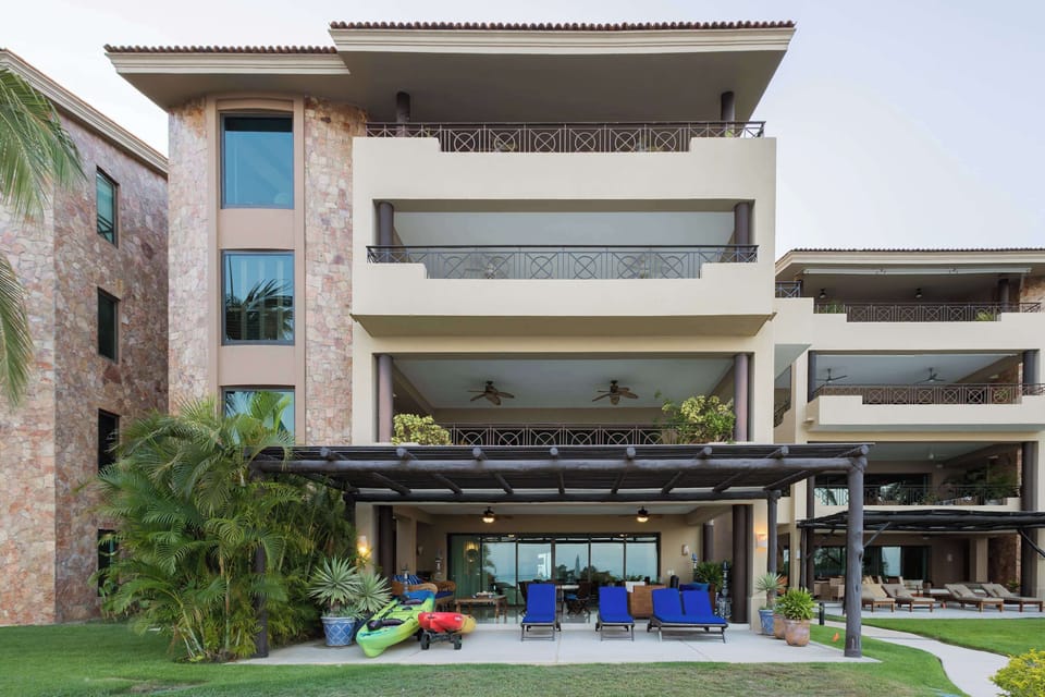 Elegant beachfront condo exterior with tropical landscaping, expansive balconies, and direct access to luxury resort-style amenities.