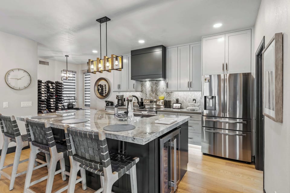 Gather in this beautifully updated chef-inspired kitchen, featuring a stunning oversized island, sleek stainless appliances, and stylish bar seating.