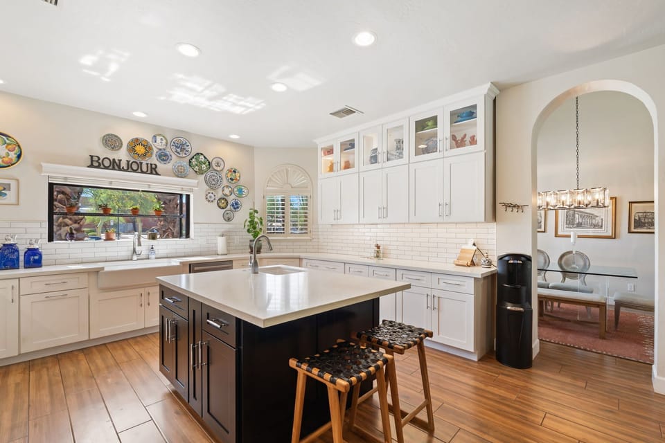 Bright chef’s kitchen with a Wolf range, bold tile backsplash, spacious island with seating, and generous counter space for effortless meals.