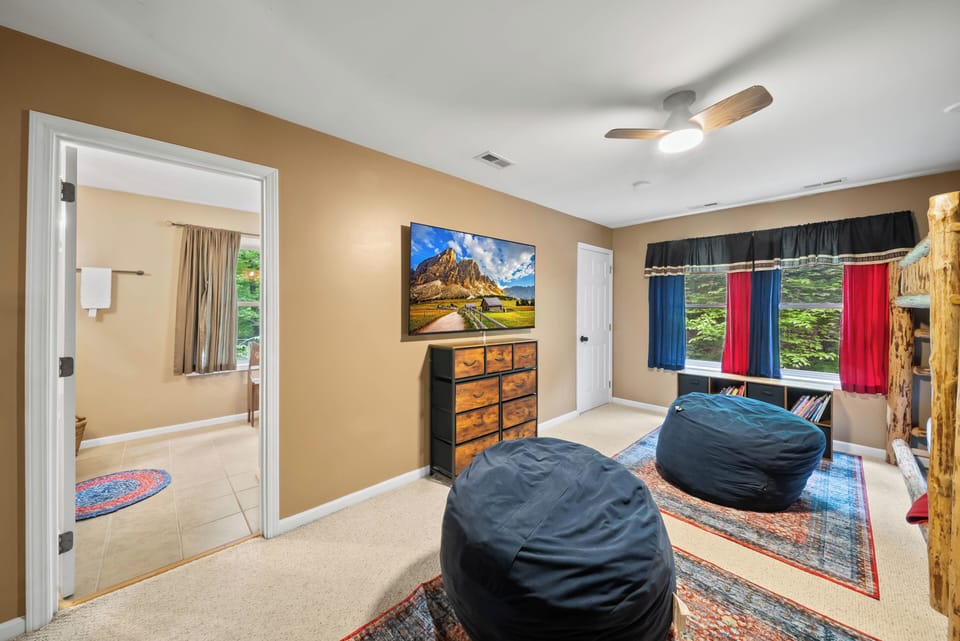 A fun hangout space for the kids at The Mountain Hearth Ii, complete with bean bag seating, a flat-screen TV, and a rustic log bunk bed.