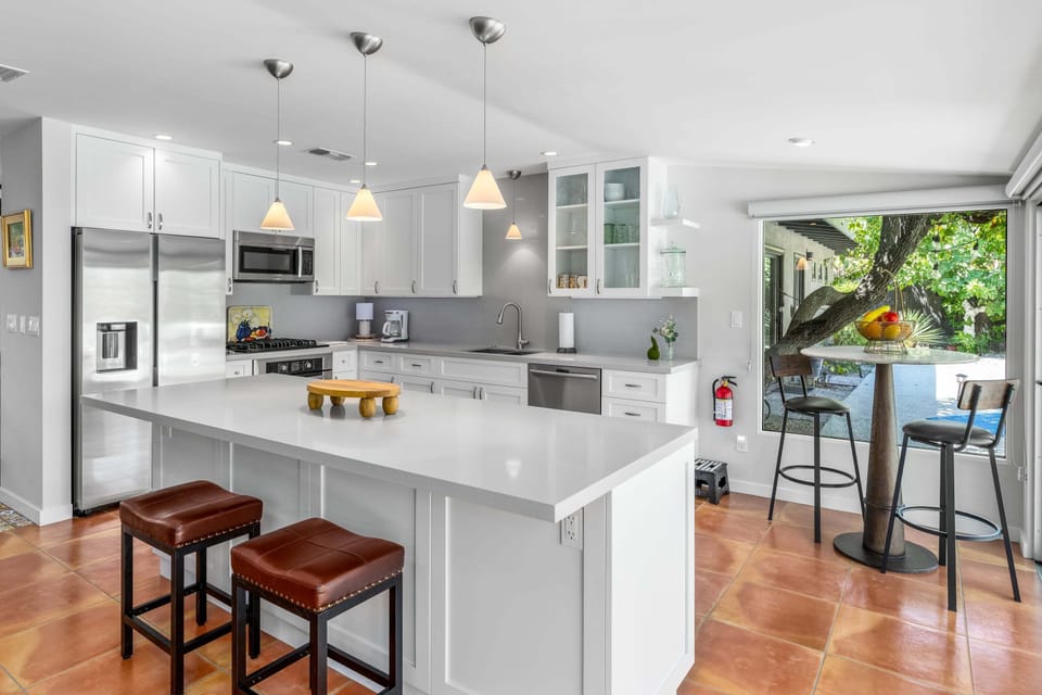 Large kitchen with island, counter seating, stainless steel appliances, and hightop seating overlooking the back patio.