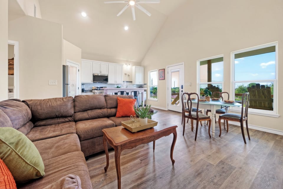 Bright open-concept living and dining area with vaulted ceilings, cozy seating, and easy deck access.