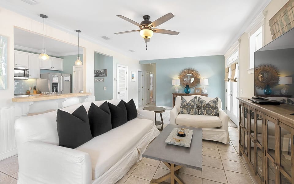 Bright beach-inspired living room with cozy seating, a TV, and coastal decor throughout.