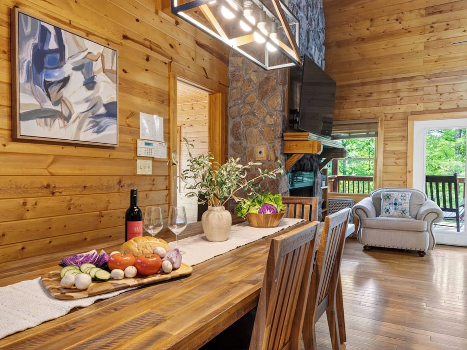 Gather around the rustic dining table after a day in the mountains, with a stone fireplace and cozy cabin ambiance nearby.