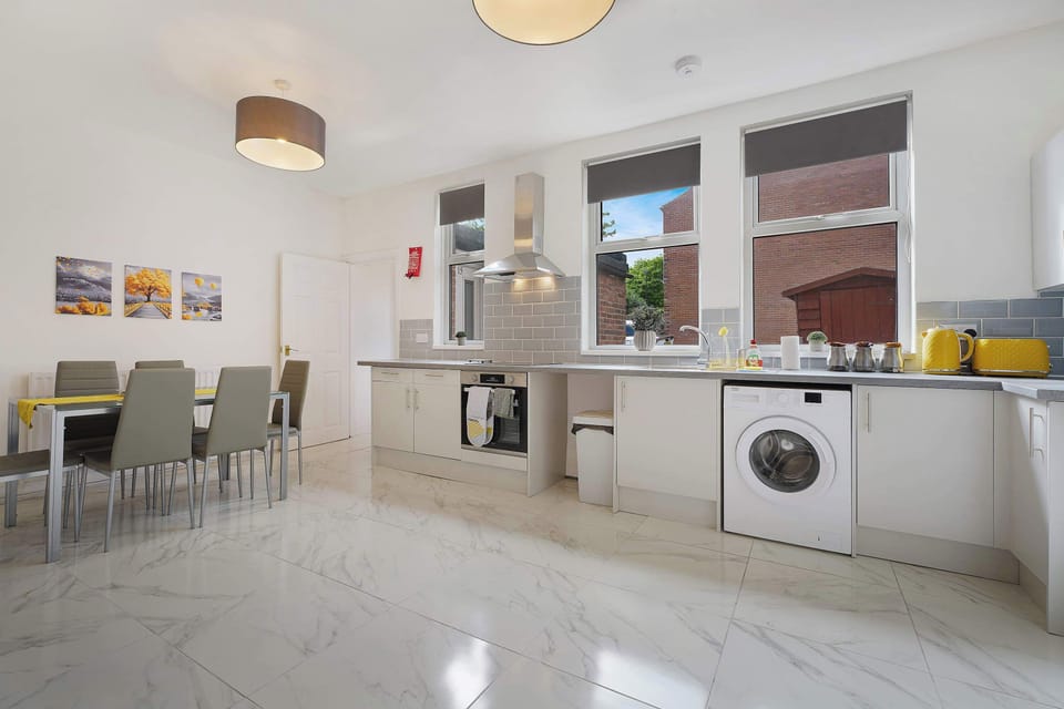Gather around this bright kitchen and dining area featuring a six-person table, modern appliances, and generous everyday workspace. Large windows and practical storage create a comfortable setup for shared meals during your stay.
