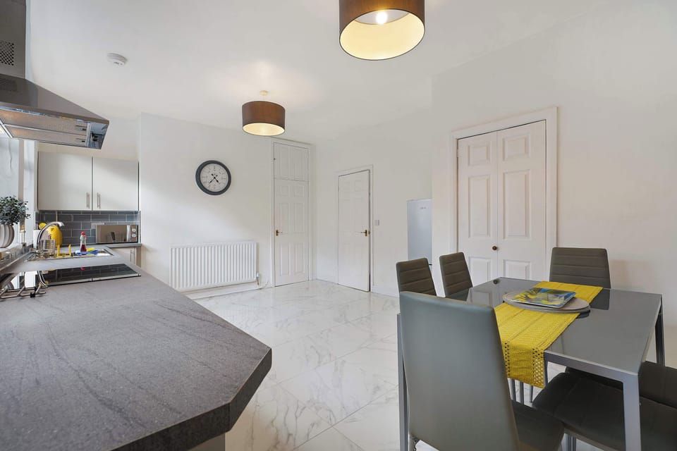 Designed for group stays, this spacious kitchen and dining area includes a six-person table, modern appliances, and useful preparation space. The open layout creates a comfortable setting for shared meals and everyday cooking together.