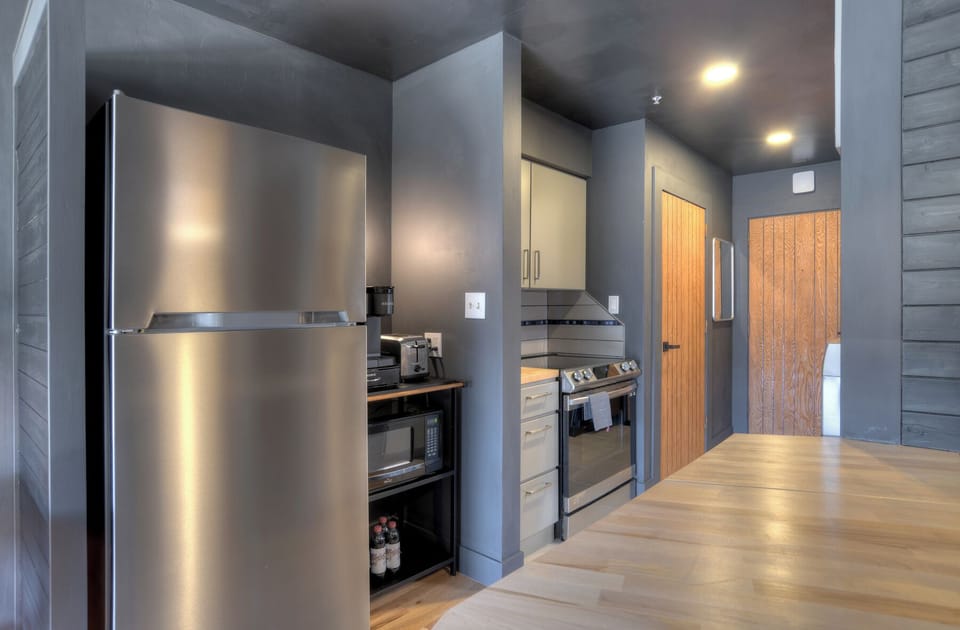 Small kitchen area with full-sized fridge, stove, oven and dish washer.