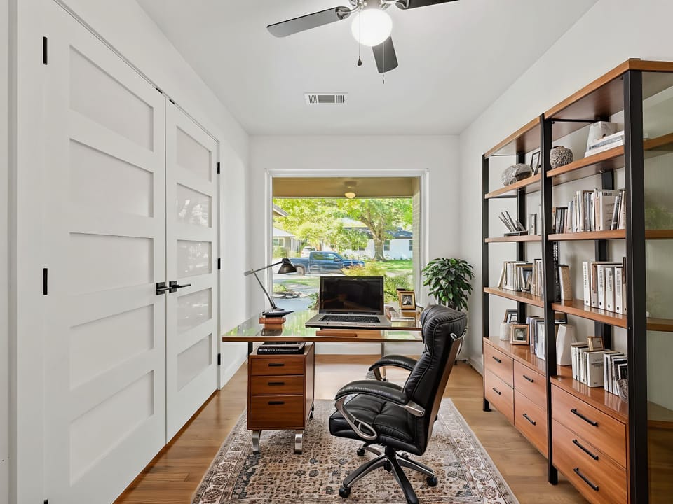 Your private office awaits with warm wood furnishings, built-in shelving, and peaceful neighborhood views to inspire productivity.
