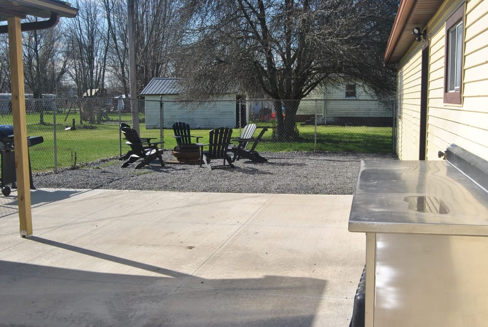 Fenced in backyard with patio and fire pit. 