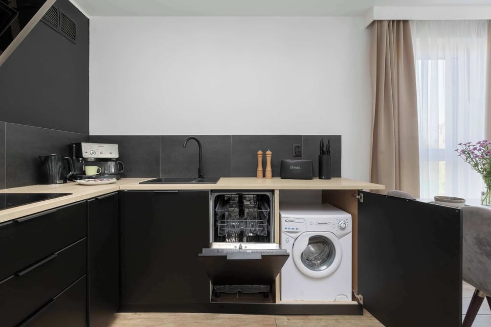 A modern kitchenette with dark cabinets and built-in appliances. The space is functional and neatly arranged.