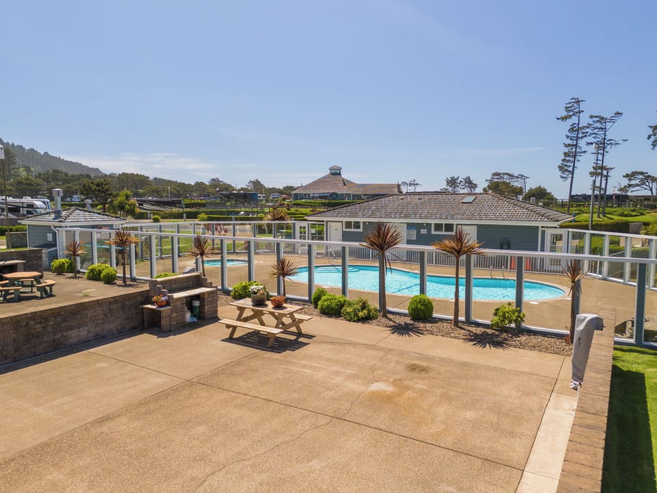 Dive into sun-soaked relaxation at your inviting outdoor pool with ample lounge space, surrounded by coastal landscaping and open skies.