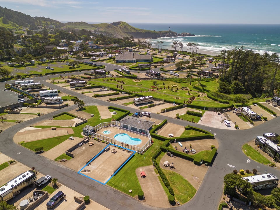 Coastal RV resort featuring organized sites, pool facility, and recreational areas with direct beach access and scenic lighthouse views along the rugged shoreline.