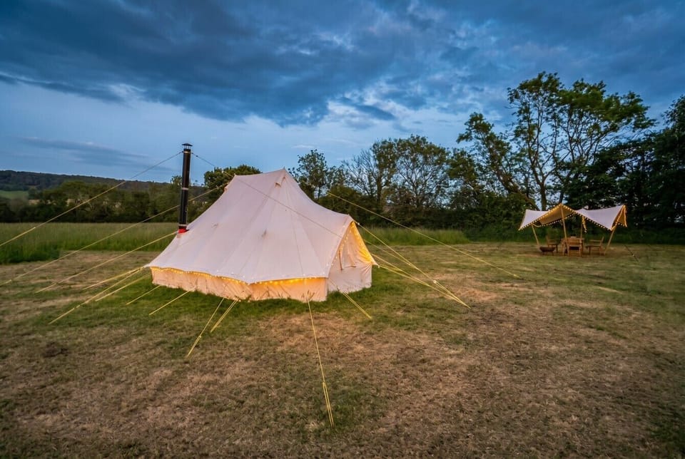 Lantern lit tent and shaded dining canopy in a peaceful open meadow