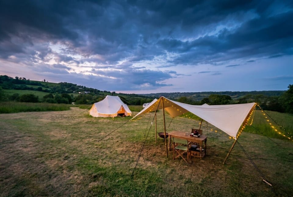 Open canvas dining shelter framing endless rolling valley views at dusk