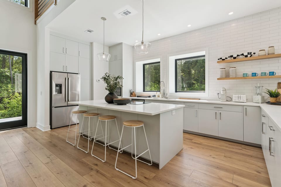 Picture yourself preparing meals in this bright, modern kitchen with sleek countertops, stylish pendant lighting, and garden views that bring natural beauty indoors.