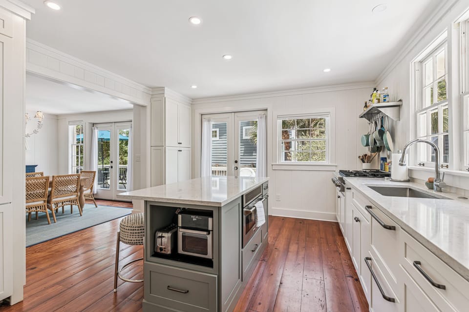 Your bright, welcoming kitchen features gleaming countertops, stainless appliances, and warm hardwood floors. Sunlight streams through multiple windows while the open layout connects seamlessly to your dining area.
