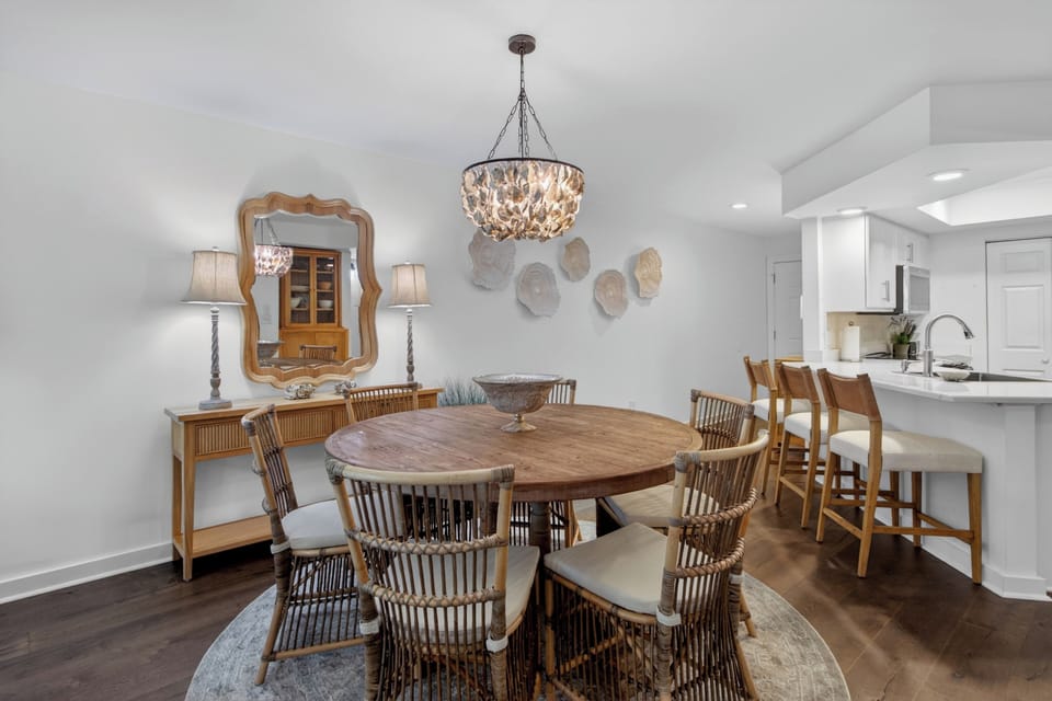 Gather around the elegant dining table beneath a stunning shell chandelier, where shared meals become cherished memories in this beautifully appointed space.