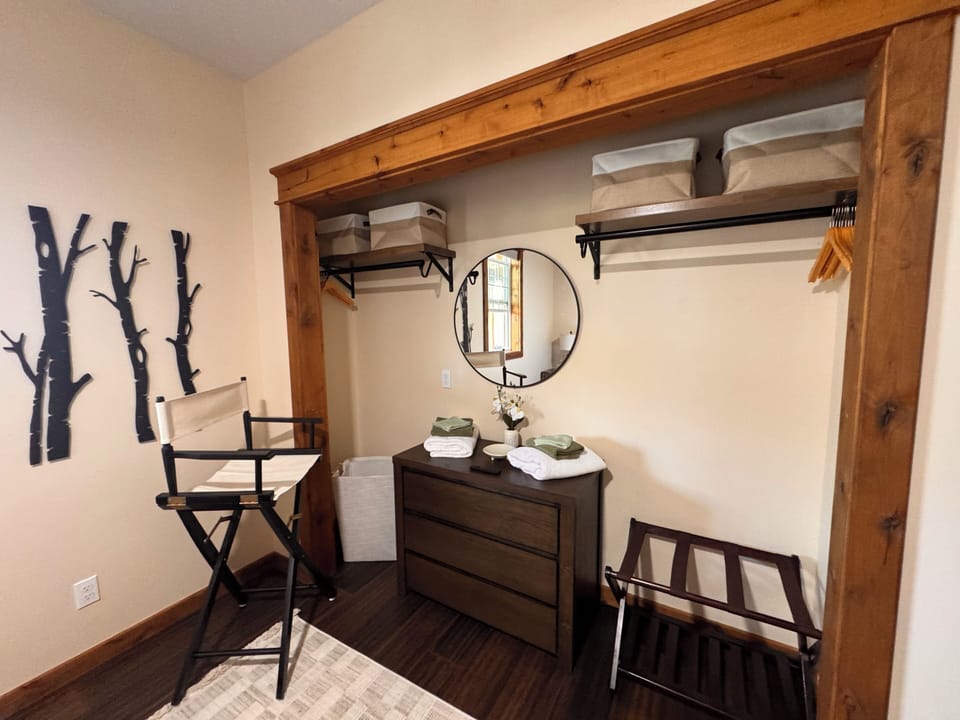 Rustic open closet with dresser, mirror, and convenient luggage rack