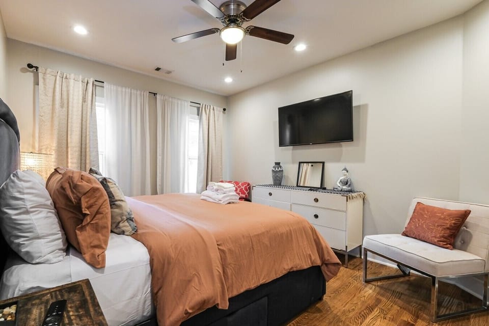 A cozy and restful space featuring a queen-sized bed, ceiling fan, and TV.