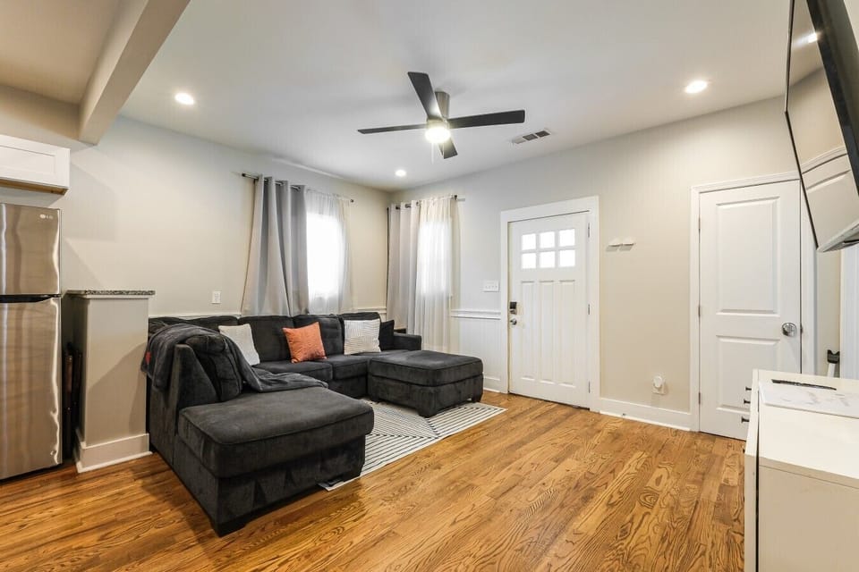 Relax on beautiful hardwood floors in this comfortable living area, featuring a ceiling fan and a smart TV for cozy movie nights.