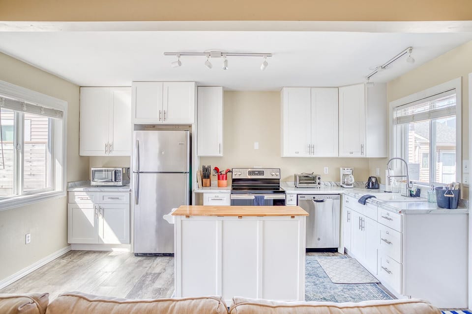 Cook your favorite meals in this bright, fully-equipped kitchen with stainless steel appliances and spacious island perfect for gathering.
