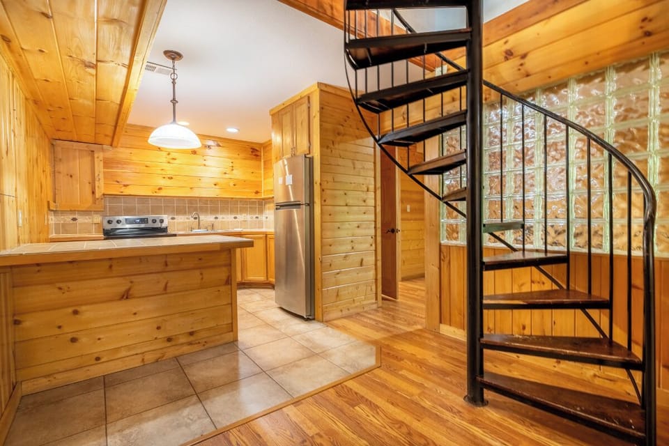 Your cozy downstairs kitchen welcomes you with warm wood tones, modern appliances, and a striking spiral staircase that adds character and charm to your retreat.