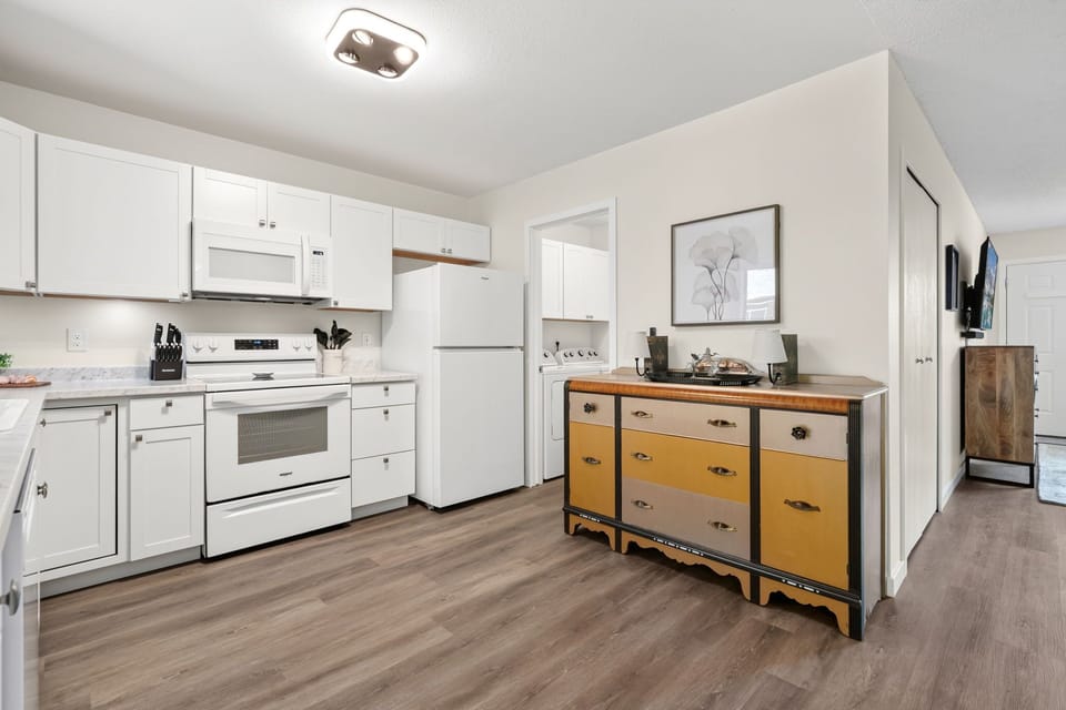 Your fully-equipped kitchen features bright white cabinetry, modern appliances, and stylish wood floors—perfect for preparing favorite meals or morning coffee in comfort.