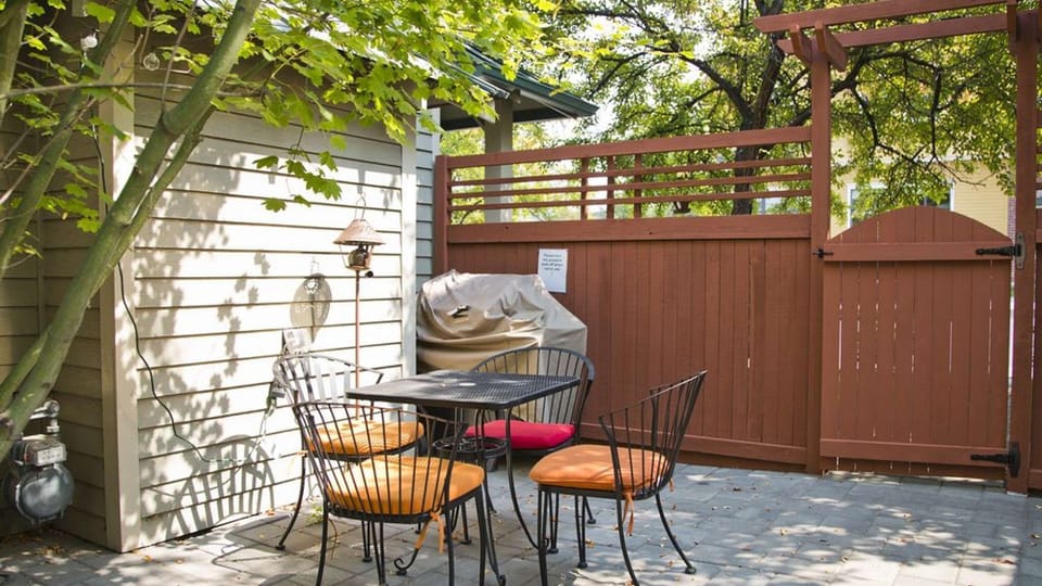 A gas BBQ grill and patio table that seats four is located in a semi-private patio area.