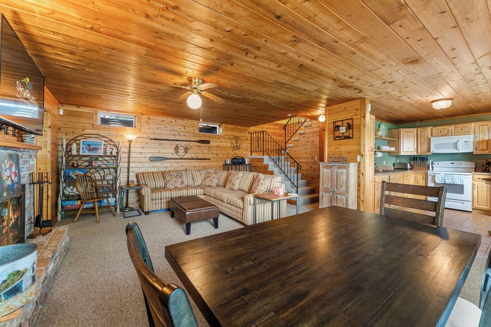 Step into your cozy cabin retreat with warm pine walls, vaulted ceilings, and an open layout perfect for gathering. Relax on the comfy sofa, share meals at the dining table, and enjoy the rustic charm throughout.